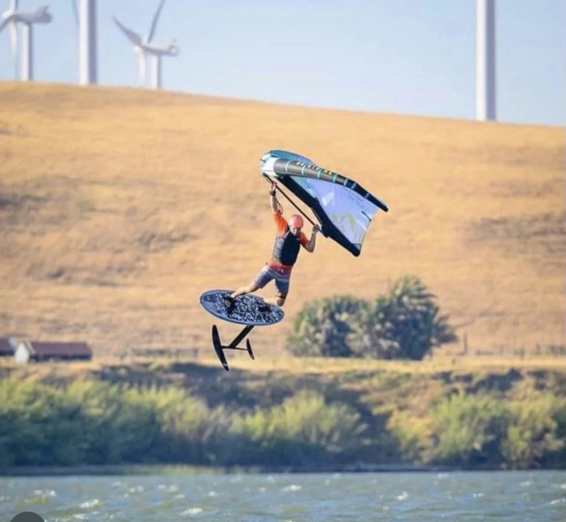 Foilboarder riding on water with wind turbines in background