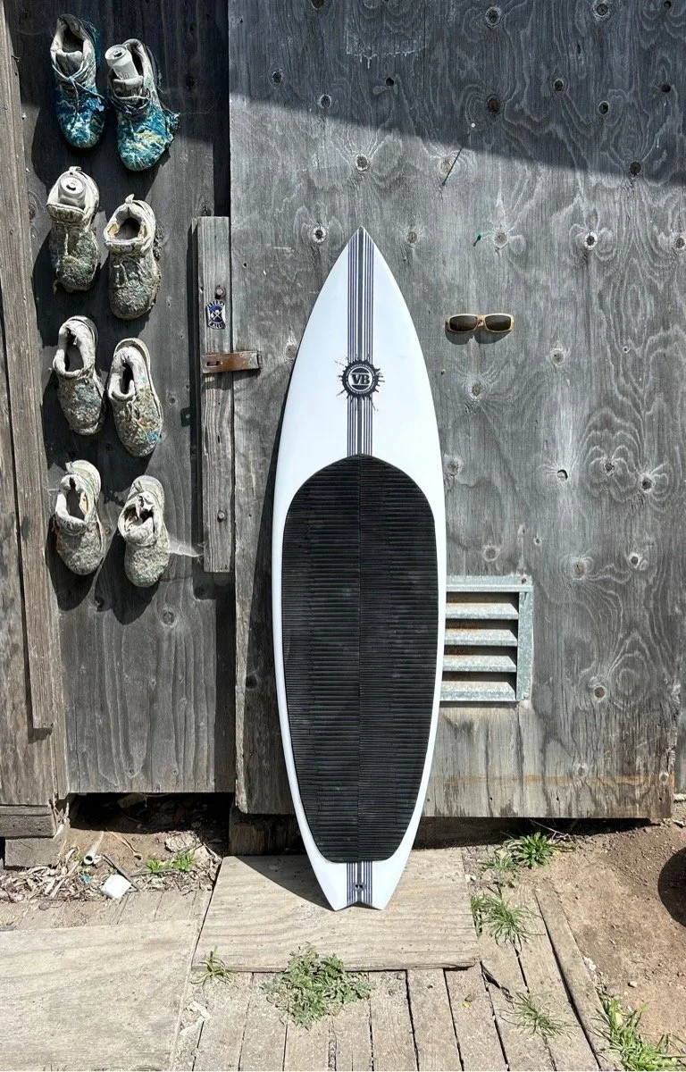 Custom kiteboard by Vince Broglio leaning against a wooden wall
