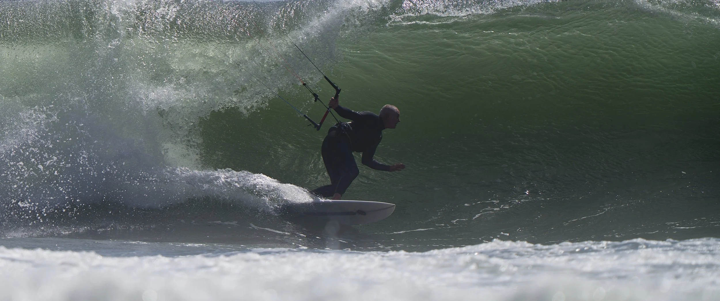Kitesurfer riding inside a wave on a Vince Broglio kiteboard